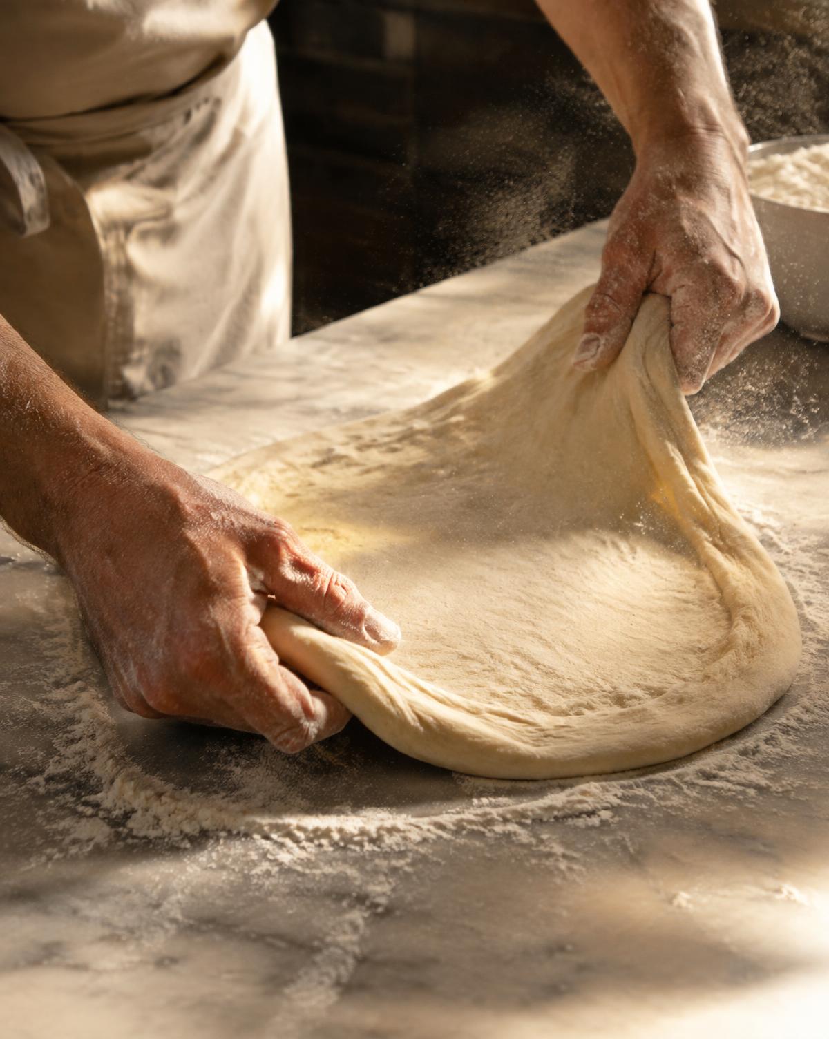 Les mains de Gino étirant la pâte